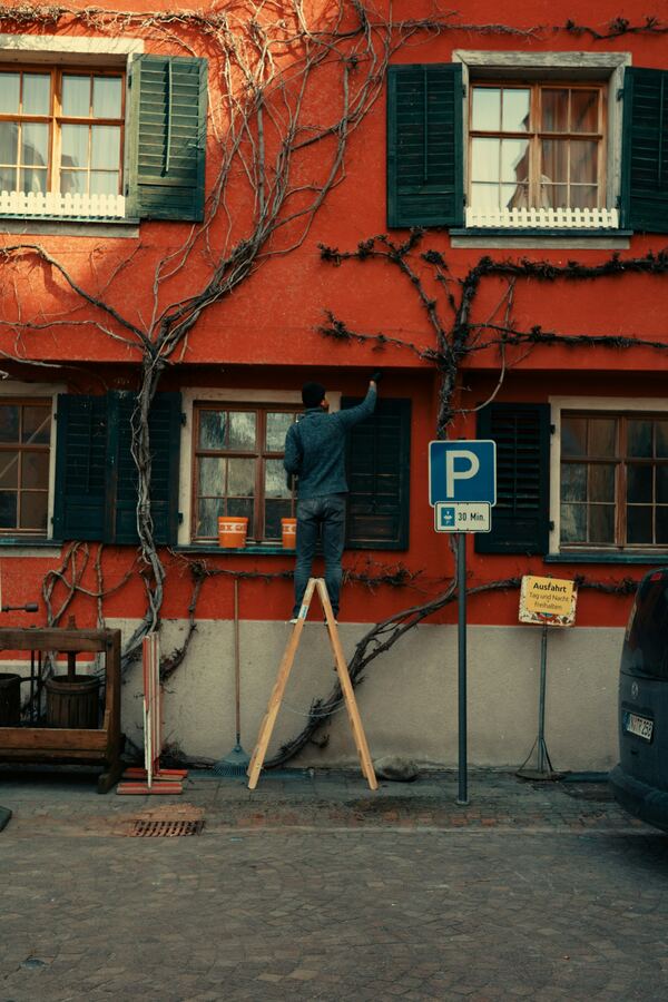 Painter painting the exterior of a building from a ladder